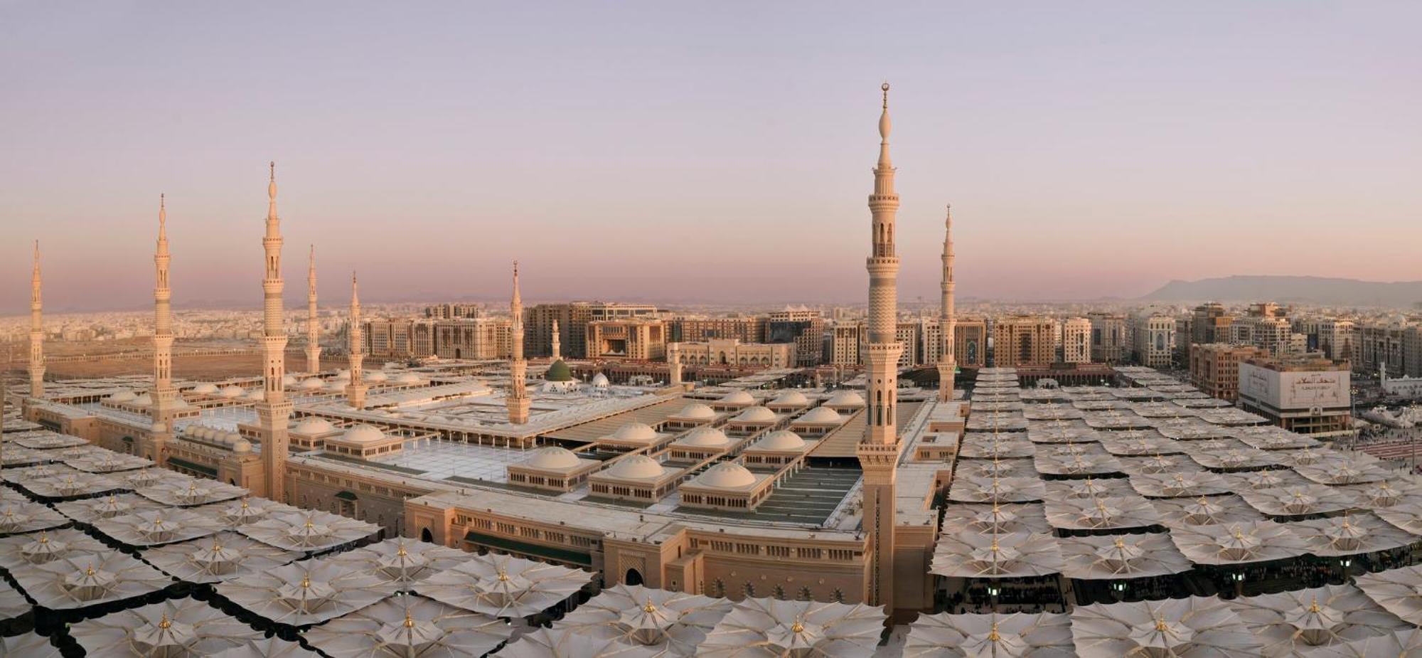 Intercontinental Dar Al Iman Madinah By Ihg Ξενοδοχείο Μεδίνα Εξωτερικό φωτογραφία The photo shows an aerial view of the Al-Masjid an-Nabawi, or the Prophet's Mosque, located in Medina, Saudi Arabia. The mosque features distinct minarets, large white domes, and expansive open areas with large umbrellas that provide shade for visito
