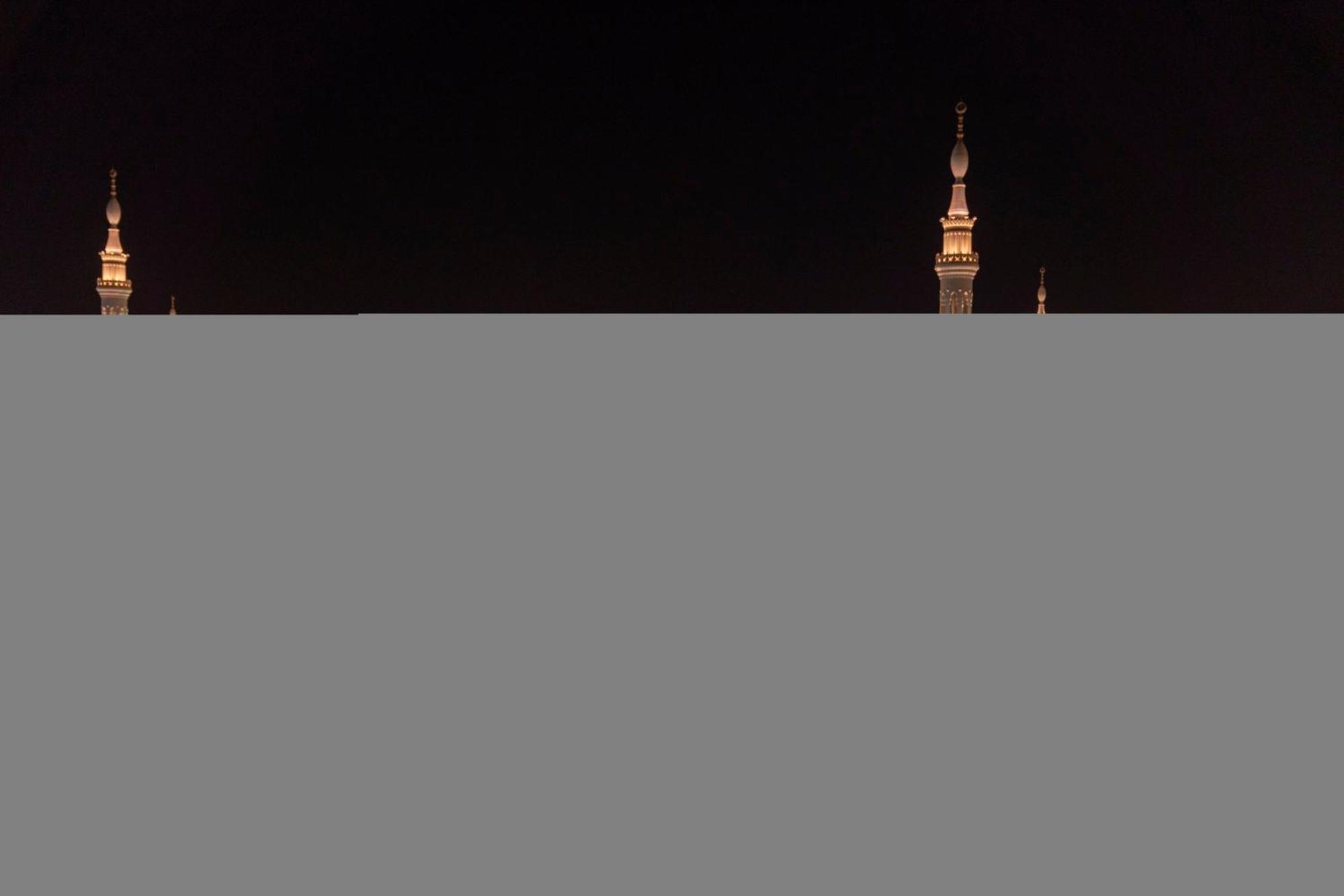 Intercontinental Dar Al Iman Madinah By Ihg Ξενοδοχείο Μεδίνα Εξωτερικό φωτογραφία The image appears to show a night scene featuring tall structures with pointed tops, likely minarets, illuminated against a dark background. The lighting creates a striking contrast, highlighting the architectural details of the structures. The overa